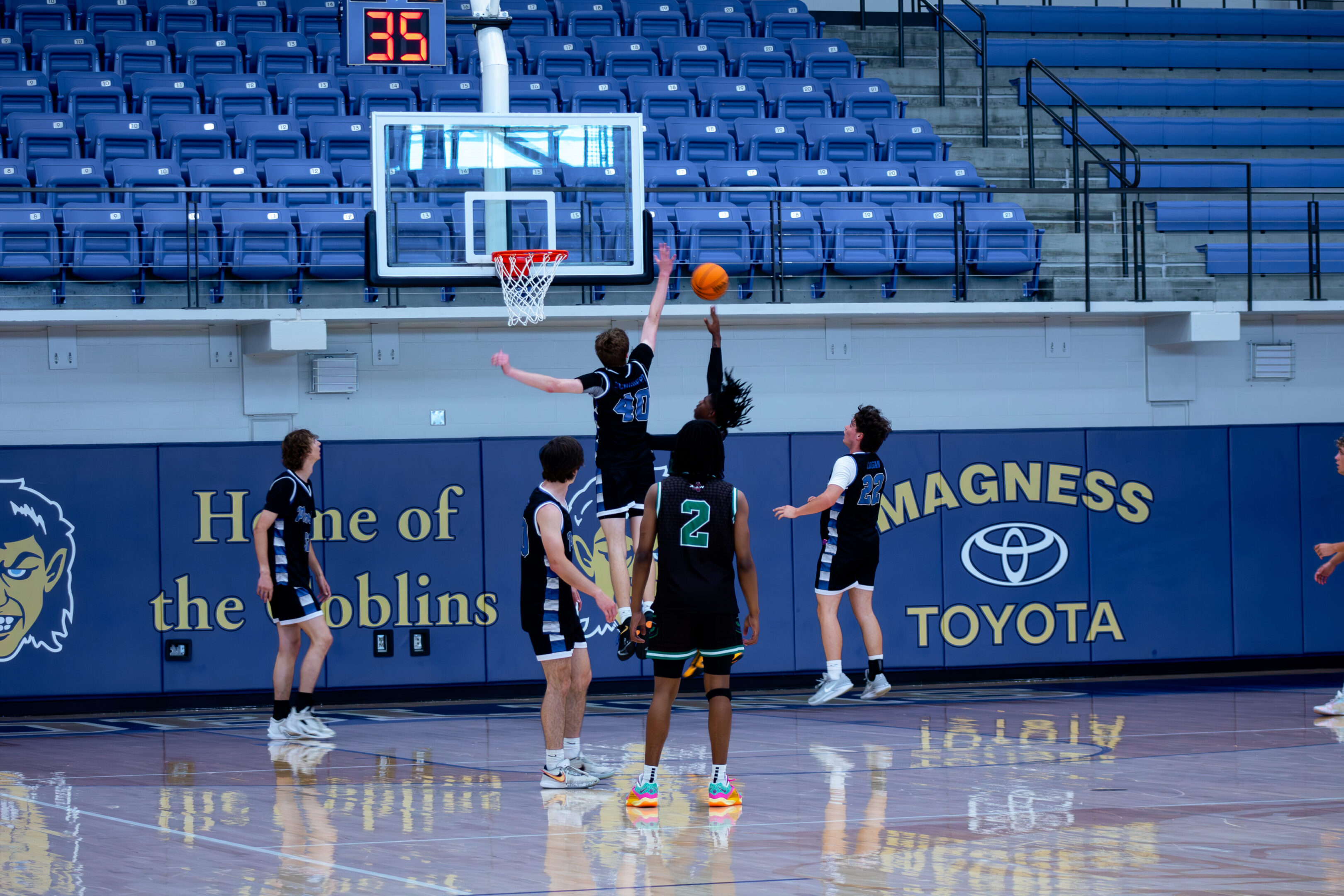 Basketball players practicing layups on an indoor court.