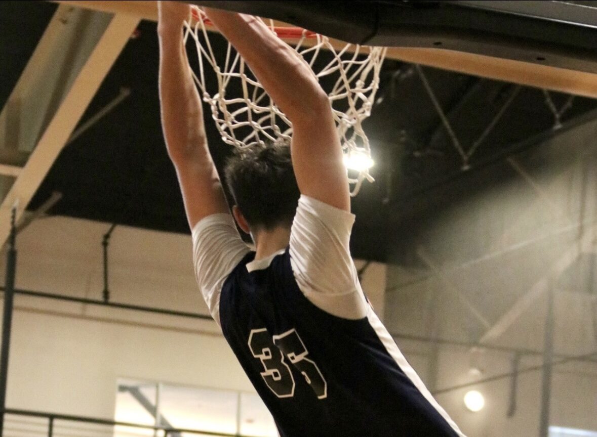 Basketball player dunking the ball during a game.