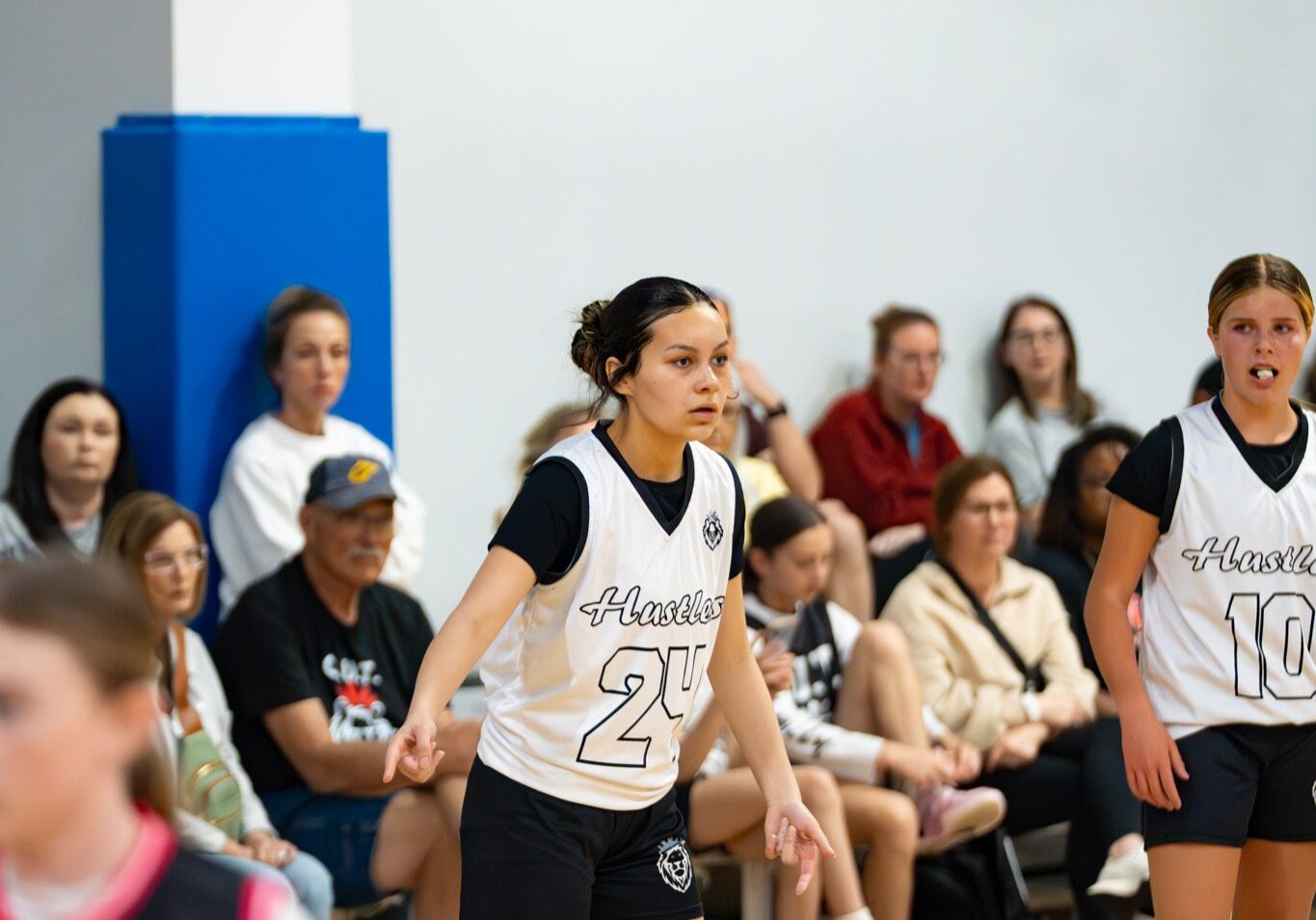 Young female basketball players in action during a game with attentive spectators.