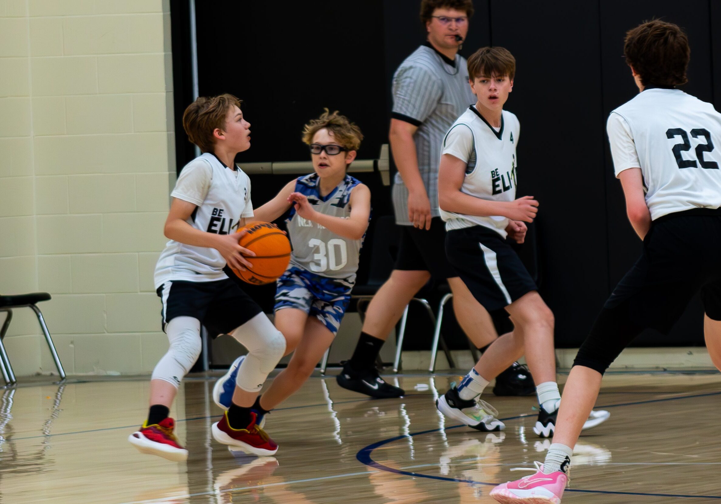 Young boys playing basketball in a gymnasium during a game.
