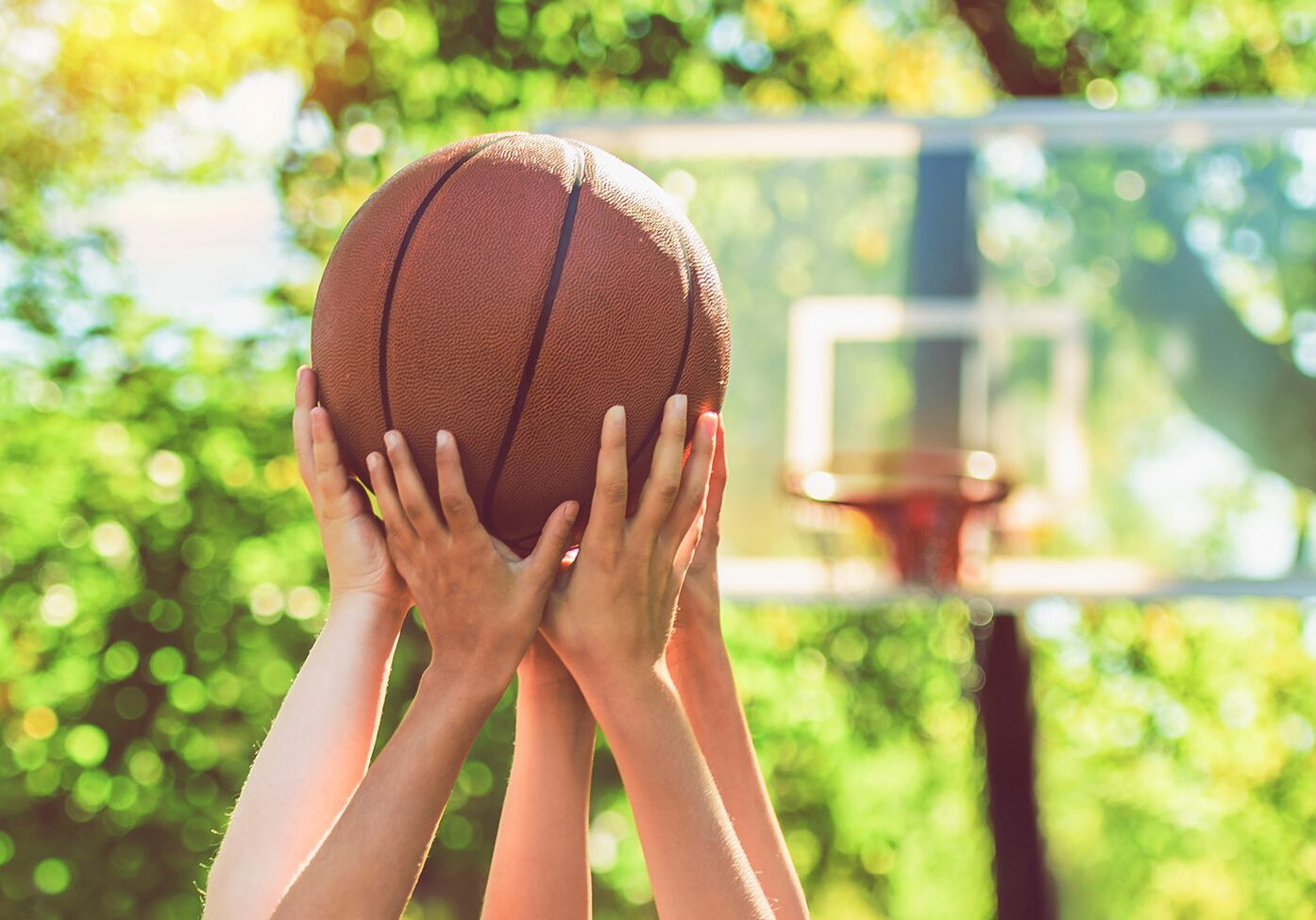 Kids playing basketball under sunny sky